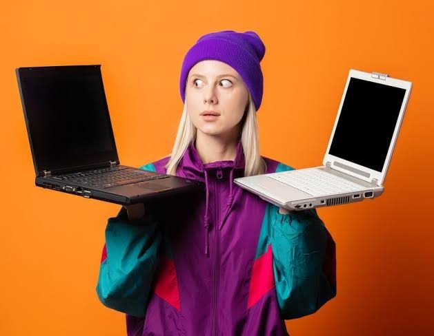 Djevojka drži dva laptopa i odlučuje između njih